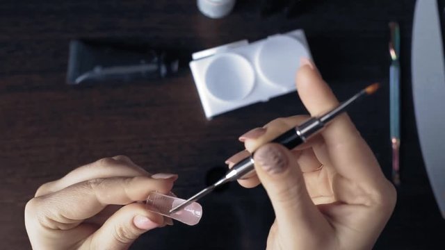 the manicurist applies gel Polish to nail tips and makes nail extension itself