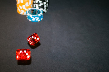 red dice in motion with Casino Chips on a black background 