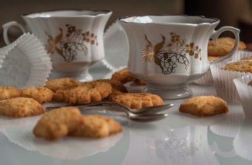 porcelain white cups with golden pattern and crumbly shortbread biscuits still life background