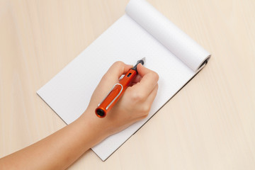 Hand Holding a Pen and Writing onto a Blank Note Pad Paper