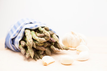 Fresh asparagus stems in a blue and white textile napkin and garlic