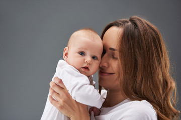 Gorgeous woman with curly hair cuddle to her small toddler