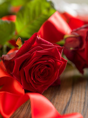 Valentine's day background with red roses and red ribbon on wood