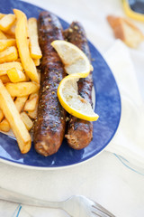 Saussages and french fries on a blue plate