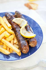 Saussages and french fries on a blue plate