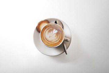 aromatic cup of Cappuccino coffee, on a saucer, with a spoon, shot from above on white, with a drop...