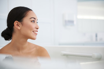 Happy smiling asian lady sitting in jacuzzi