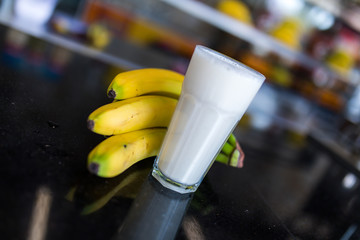 Banana smoothie or milk shake on the table with bananas