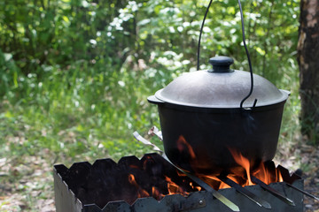 Cooking on an open fire. Kulish, kulisz - millet porridge with meat, potatoes, onion, garlic, herbs, salt and spices. Cooking Ukrainian national dish in metal pot on an open fire, outdoor
