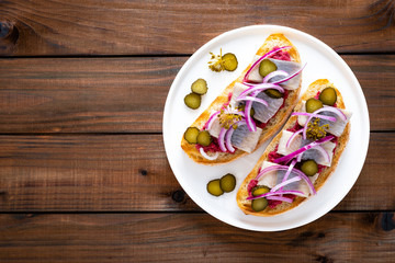 Delicious grilled sandwiches with herring, onion and beetroot sauce with horseradish on dark wooden rustic background. Danish cuisine. Top view