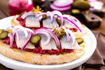 Delicious grilled sandwiches with herring, onion and beetroot sauce with horseradish on dark wooden rustic background. Danish cuisine