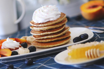 Breakfast pancakes served with honey and fruits