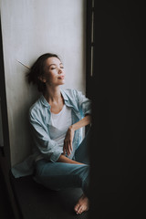 Relaxed young lady smiling while sitting with her eyes closed