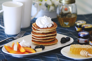 Breakfast pancakes served with honey and fruits