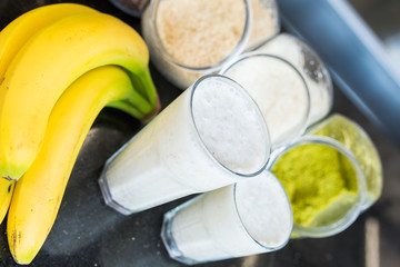 Banana smoothie or milk shake on the table with bananas