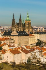 Fototapeta na wymiar Prague, Czech republic / Europe - February 15 2019: View of Prague castle, St. Vitus Cathedral and historical buildings with red roofs, sunny evening, blue sky, vertical image