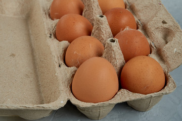 Recycled paper container on gray table with rustic brown eggs