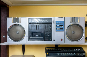 Obraz premium Silver vintage radio on white wooden shelf against yellow background.