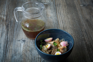 noodles dish with shiitake mushrooms, eggs, wheat sprouts and pitcher with broth