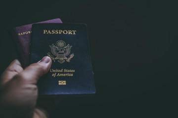 One human hand holding a red Chilean passport and a blue American passport
