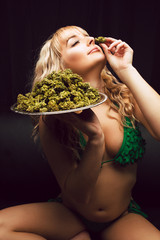 Blonde caucasian woman in cannabis bikini poses with tray of marijuana buds - 249624167