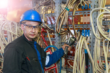 An electrician checks with a thermal imager the temperature of the power cable in an energy installer.