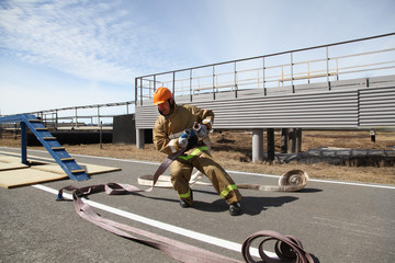 A professional fireman in a special suit jumps over a barrier .Regional fire-fighting in the training area with urban and contract firefighters.