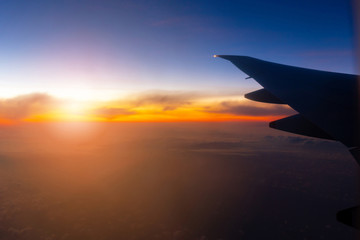 Naklejka na ściany i meble Silhouette of Airplane wing view out of the window the cloudy sunset sky background, Travel and Holiday vacation concept