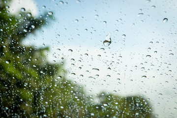 Rain drop on window glass with sky in background close up.