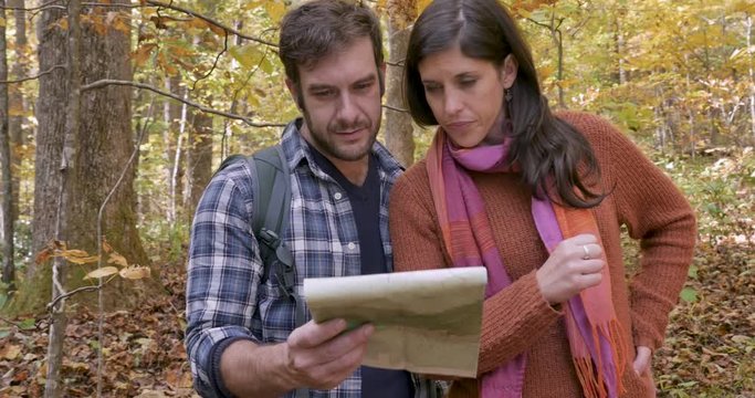 Couple lost in the woods looking at a paper map and talking about their location