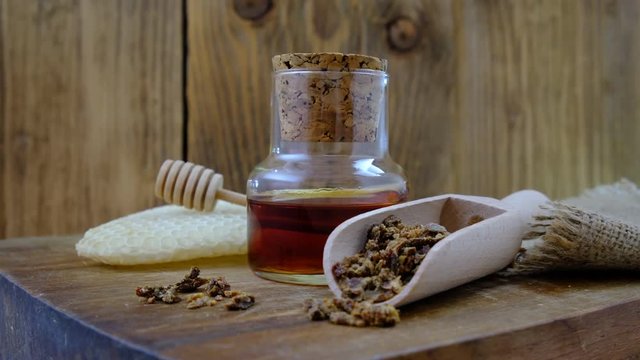 A bottle of propolis tincture and a wooden scoop of propolis granules. Medical preparations bee propolis. Bee glue. Apitherapy. How to treat bee products.