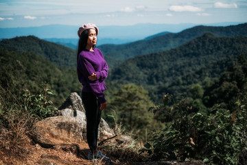 Young woman standing on mountain top and contemplating landscape