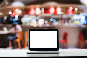 Obraz premium Mockup blank screen laptop on wood table with blurred coffee cafe background. Blank screen for graphics display montage.