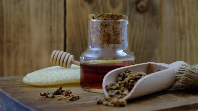 A bottle of propolis tincture and a wooden scoop of propolis granules. Medical preparations bee propolis. Bee glue. Apitherapy. How to treat bee products.