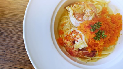 Spaghetti Carbonara with shrimp and cheese in white plate on wooden table with copy space background. Top view food photography