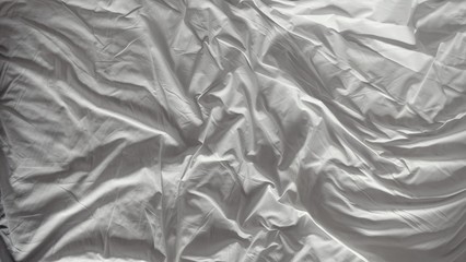 close up top view of white pillow on bed and with wrinkle messy blanket in bedroom, from sleeping in a long night. abstract texture for white background