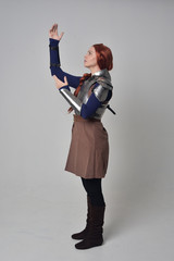  full length portrait of a  red haired girl wearing medieval warrior costume and steel armour,...