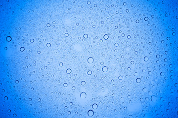 Rain droplets on blue glass background, Water drops on blue glass.