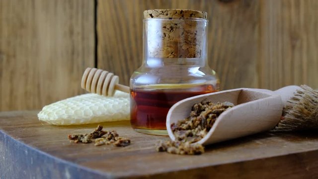 A bottle of propolis tincture and a wooden scoop of propolis granules. Medical preparations bee propolis. Bee glue. Apitherapy. How to treat bee products.