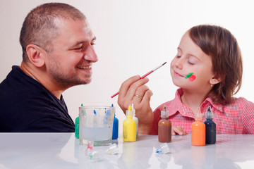 Humorous photo of parental upbringing. Funny portrait of father doing an make up her daughter. Happy childhood, family and art concept.