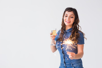 People, celebration and holiday concept - Lovely woman with sparkler and glass of champagne over white background with copy space