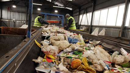 Workers at the waste processing plant. Sorting trash on a conveyor belt.