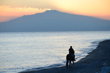 Fototapeta na wymiar Cavalcata meravigliosa al tramonto con la vista dell'Etna.
