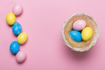 Colorfull easter eggs in nest on pastel color background with space. Concept