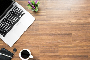 Wood office desk table with laptop computer, cup of cofee and supplies. Top view with copy space,...