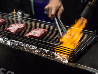 Close up hand of chef using flame torch burn on Japanese wagyu beef.