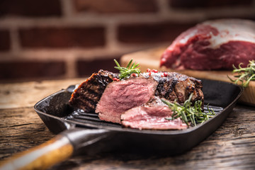 Grilled beef steak in grill pan with herbs rosemary on wooden table
