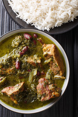 Authentic Ghormeh Sabzi dish of lamb stew meat with herbs and beans close-up in a bowl and rice. Vertical top view