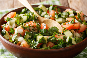Shirazi salad of fresh vegetables and herbs close-up on a plate on the table. horizontal