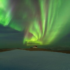 This beautiful northern lights or aurora borealis in Iceland was taken at or around house near Reykjavik during a winter night. Starry sky with polar lights. Green northern lights background